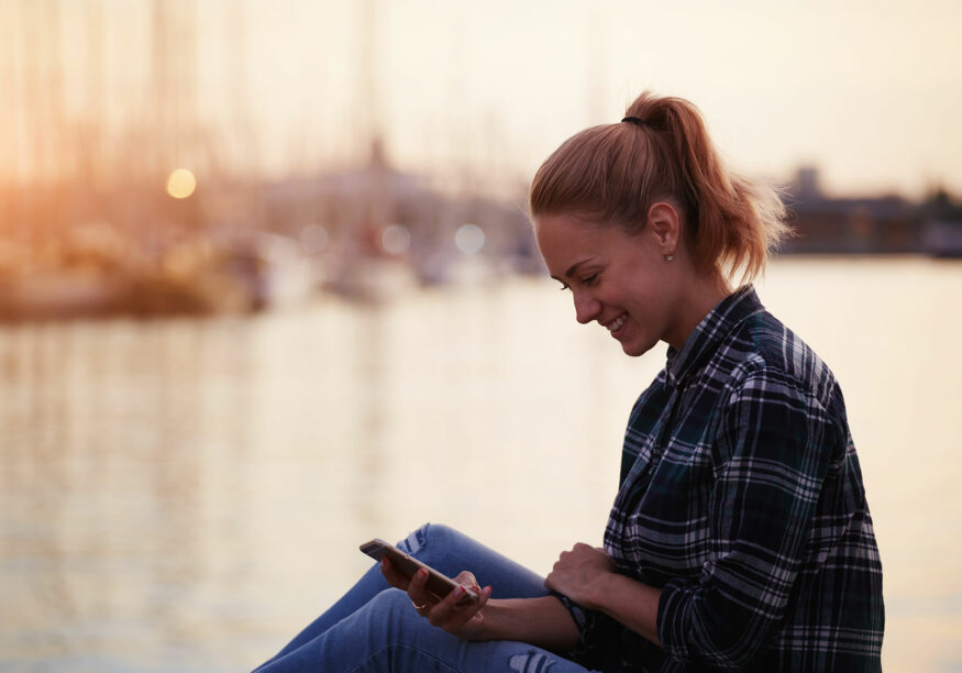 Frau mit Mobile am See